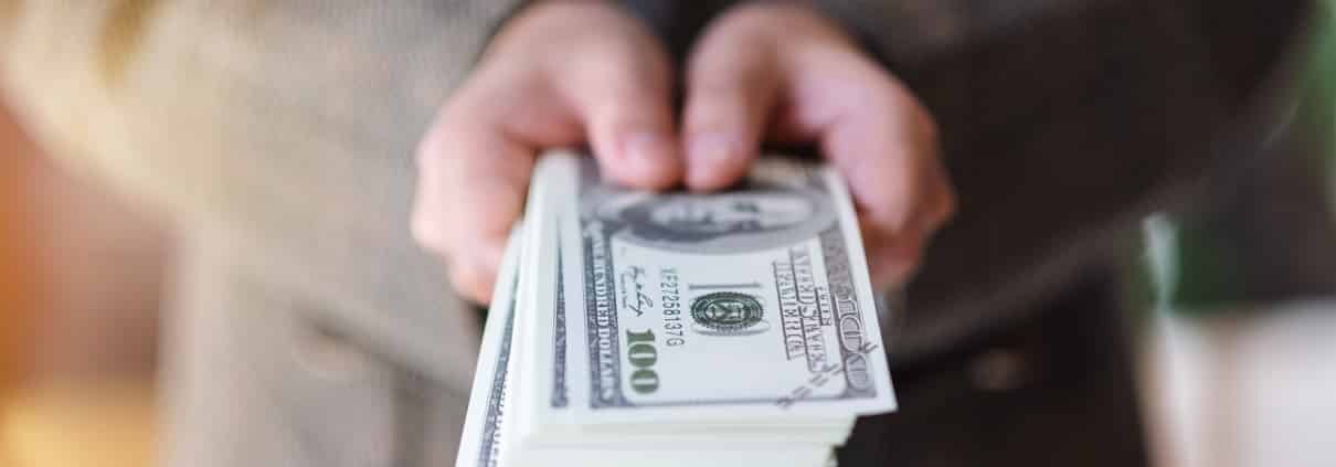 a woman holding and showing American dollar banknotes for money